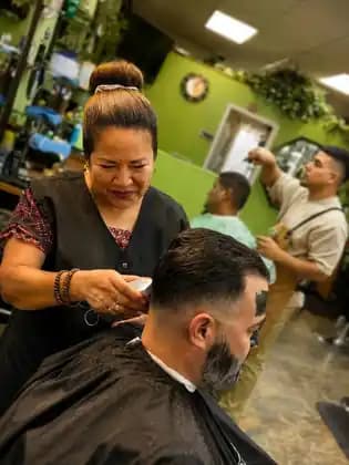 Mari using clippers while other haircuts are underway at Tijeras Barbershop